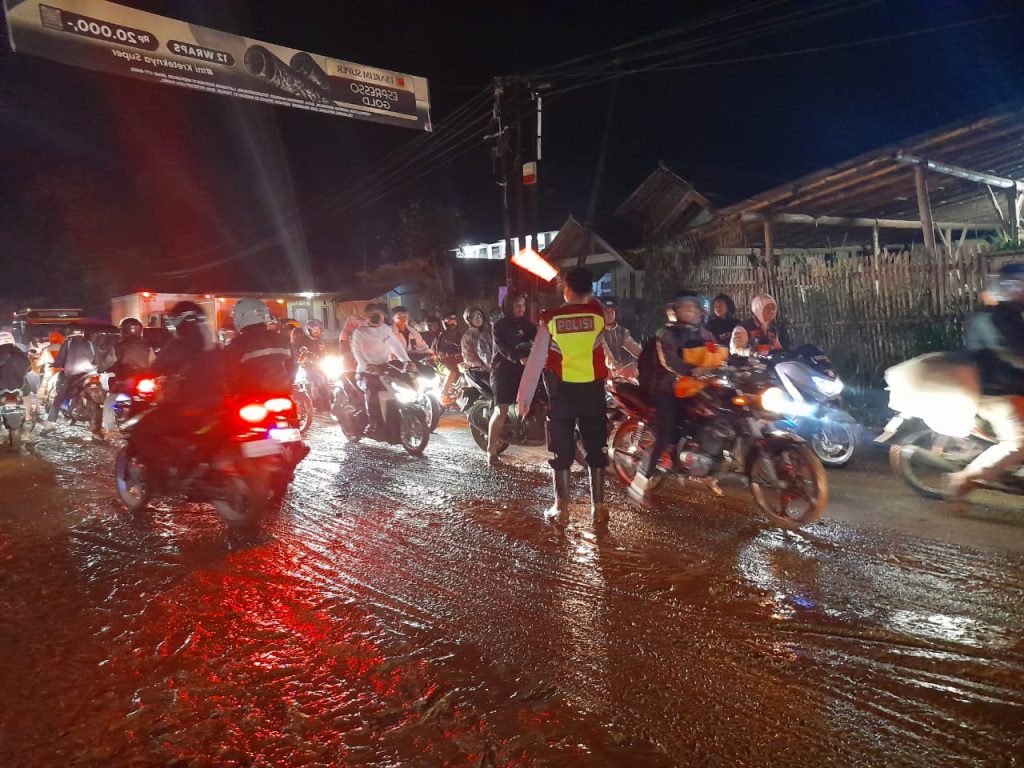 Polisi Bersihkan Lumpur Bekas Banjir Di Jalan Raya Cisurupan